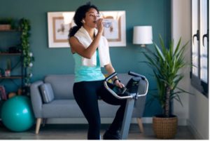 Woman exercising at home on cycling machine.
